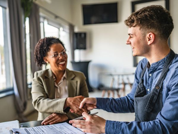 Two professionals smiling and shaking hands over a document.