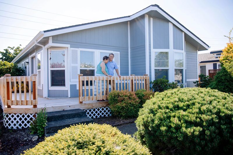 A late 50s aged caucasian couple enjoying a sunny summer morning in their front yard and front porch of their mobile home community. Shot with all natural light in Vancouver Washington, USA.