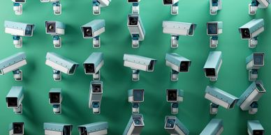 Multiple security cameras mounted on a green wall, all directed outward.