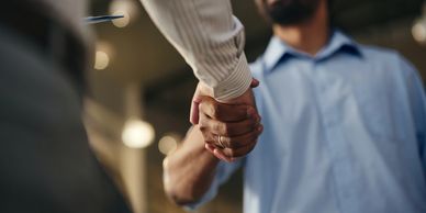 Two men shaking hands, one wearing a wedding ring.
