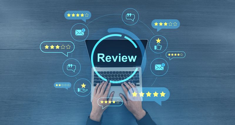 Hands typing on laptop with glowing digital review icons and star ratings on blue wooden surface, representing feedback and customer opinions