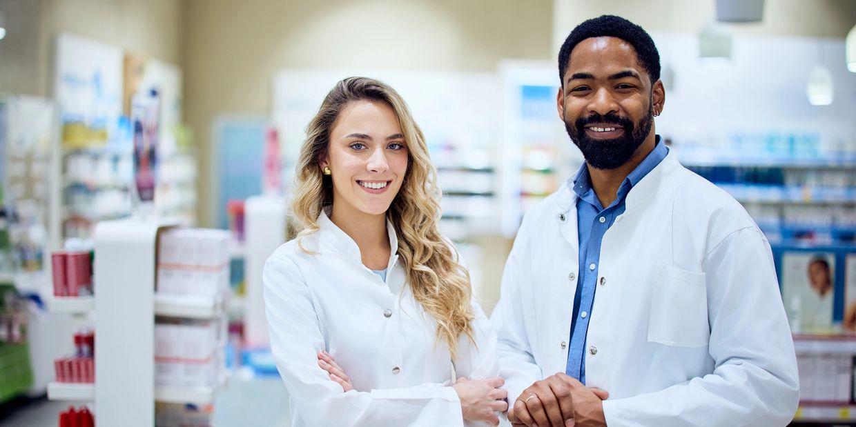 Two pharmacists smiling in a pharmacy.