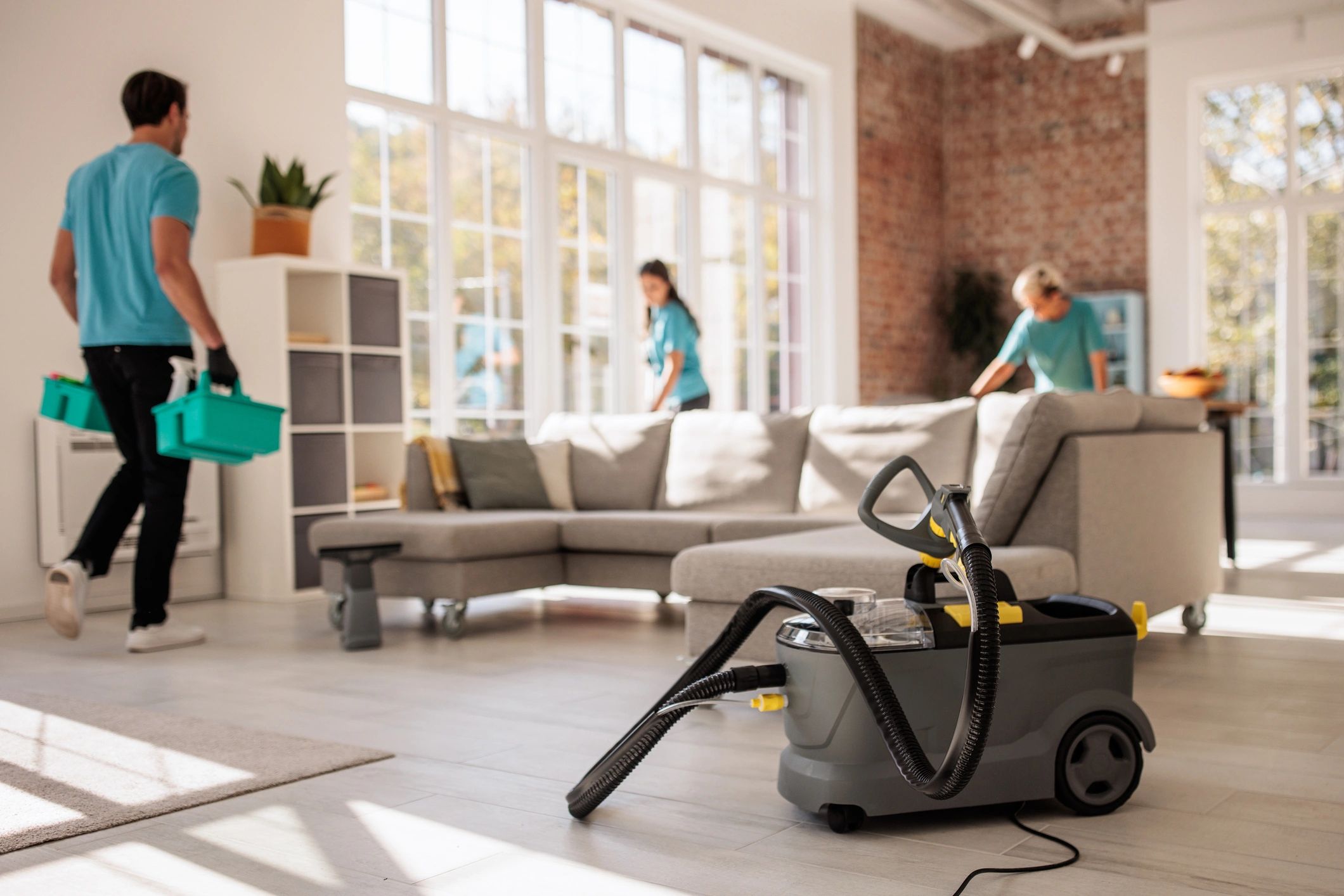 Cleaning team working in a bright living room with professional equipment.