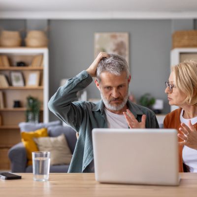 Mature couple discussing something on a laptop at home.
