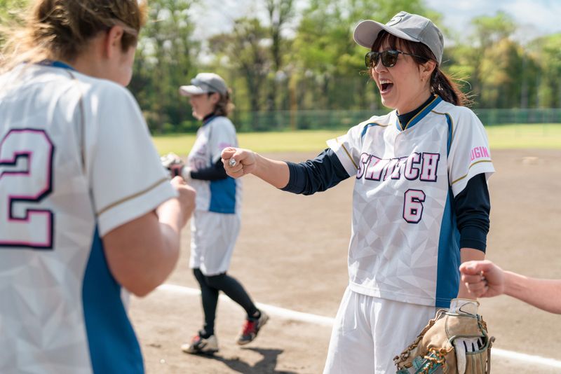 Female athletes rejoice in camaraderie and practice as a team on a sunny Tokyo field, experiencing fun and unity.