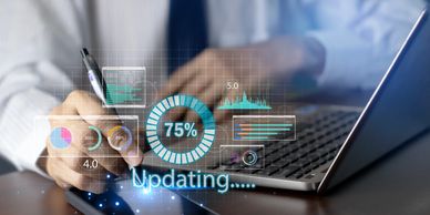 Person using laptop and smartphone with digital data update graphics overlay.