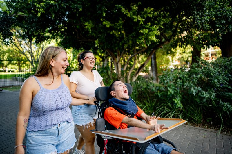 Family walking and talking on the public park- including a wheelchair young man with mental illness