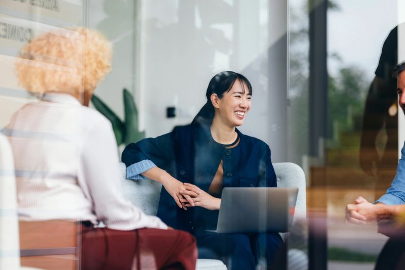 Three colleagues collaborate in a modern office, fostering a friendly and professional atmosphere. The teamwork highlights diversity, communication, and innovation for achieving shared goals and strengthening relationships.