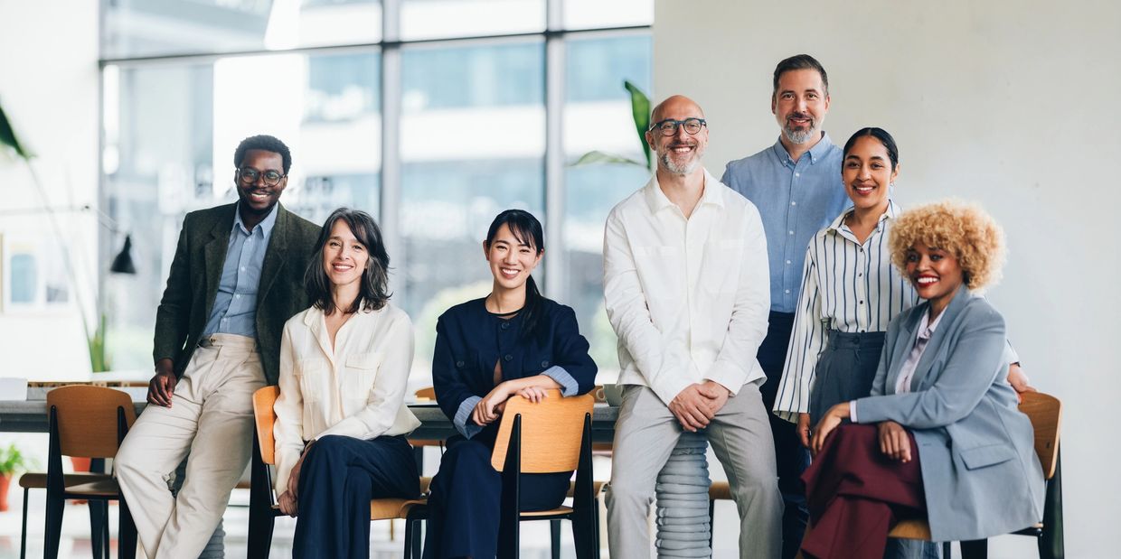 A diverse group of professionals smiling and posing in a modern office space.
