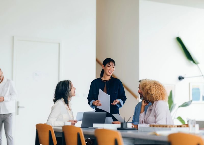 A group of diverse professionals engaging in collaboration and discussing ideas at a stylish, modern office setting during a business meeting.