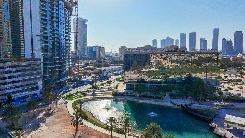Drone point of view - Panorama od Dubai with lakes (!) and awe public park with palms anf green grass lawns and skyscrapers. Fountain in lake.  Jumeira districtroad, fountain