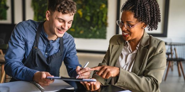 Two people smiling and discussing with a tablet.