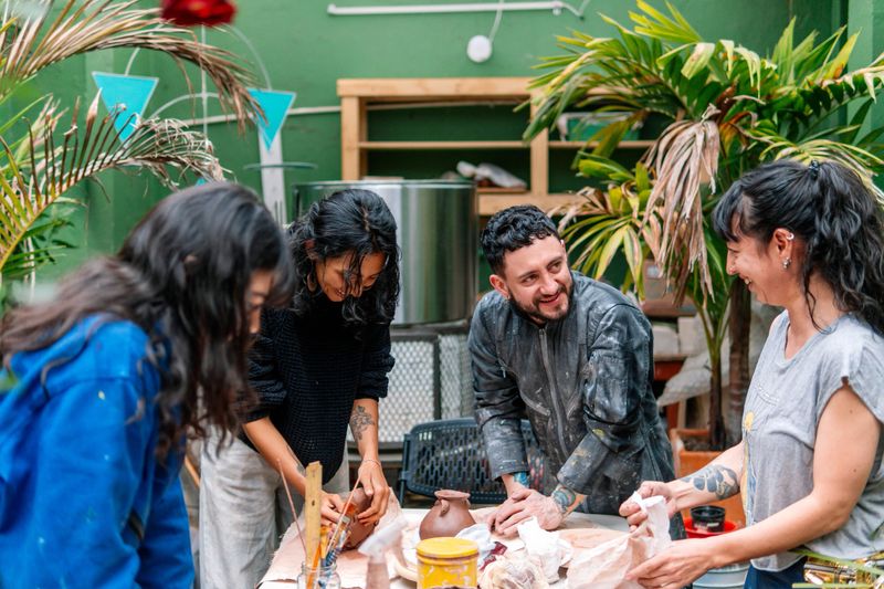 Latin American potters happily creating earthenware in their pottery workshop, celebrating tradition and craftsmanship in a vibrant community