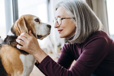 An elderly woman lovingly looks at her dog indoors.