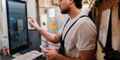 Man working on a touchscreen computer in an industrial setting.