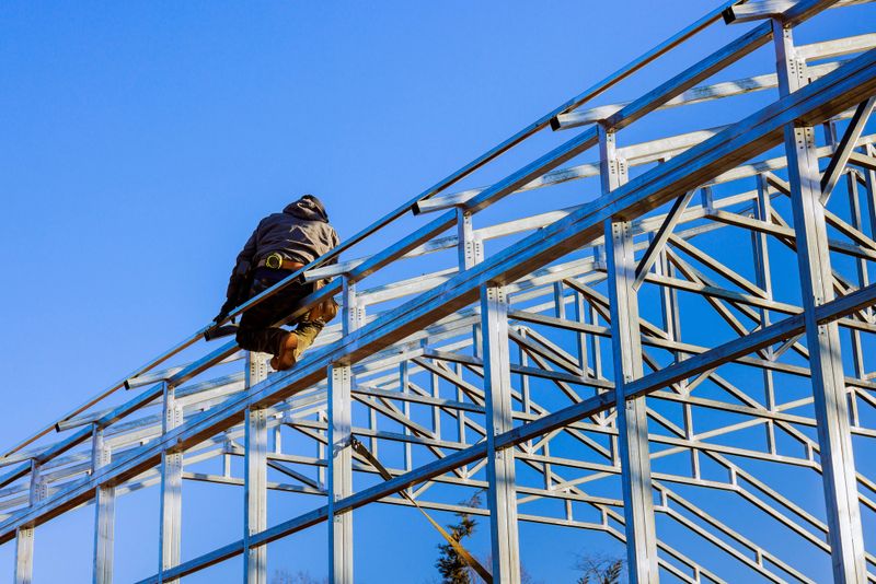 Construction worker is assembling framework metal structure of building commercial storage