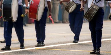 Uniformed marching band drummers during a parade | VisitBronzeville