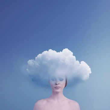 A woman with a cloud covering her head against a blue sky.