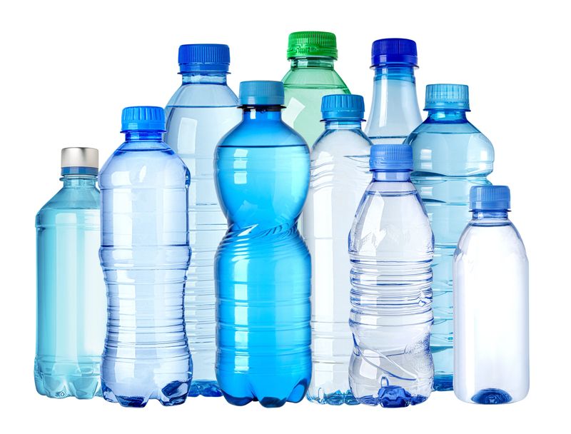 Various plastic water bottles are standing on a seamless white background, creating a composition