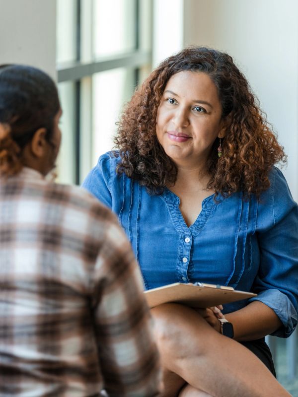 A counselor attentively listens to a client during a therapy session.