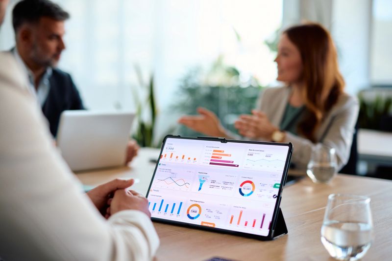 Business colleagues are having a discussion about financial data displayed on a digital tablet during a productive meeting in a modern office