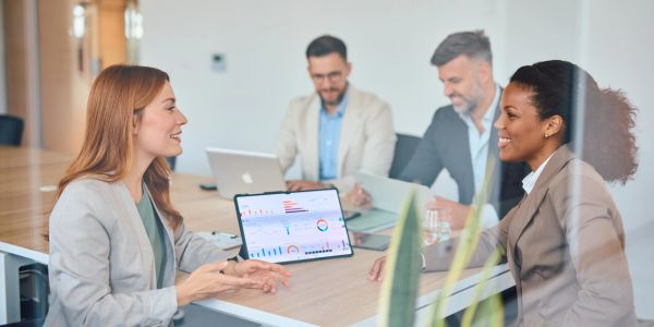 Two women discussing data in a meeting room.
