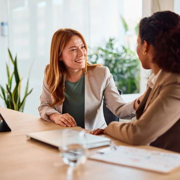 Two women engaged in a supportive conversation at a desk.