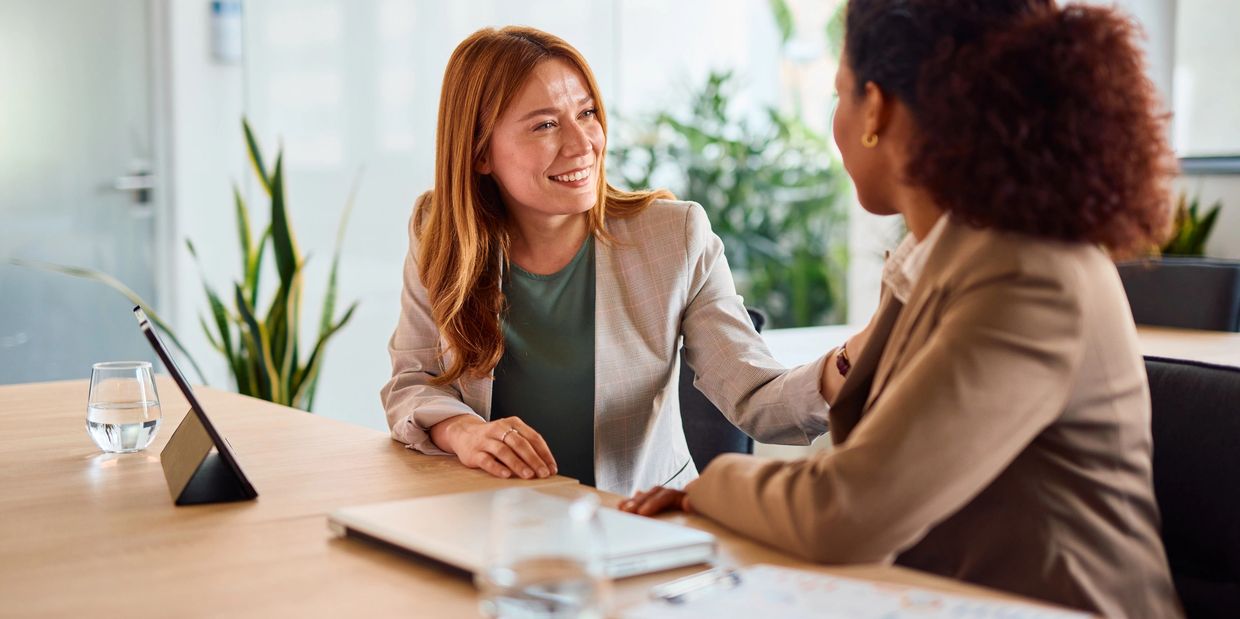 Two women having a friendly conversation in a bright office setting.