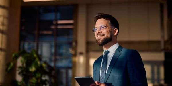 Smiling businessman holding a tablet in an office.