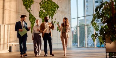 Four professionals walking and discussing in a modern office.