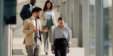 Four business professionals walking down stairs in conversation.