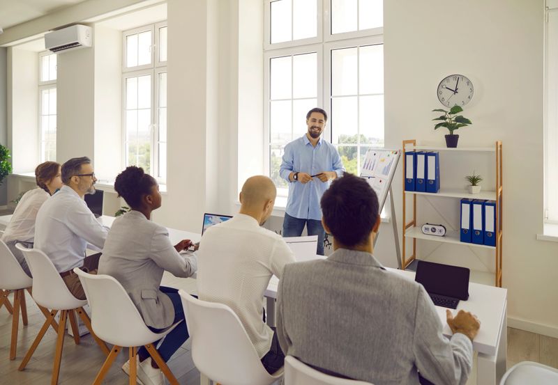 Man teacher business couch teaches communicates with a group of adult students in modern office.
