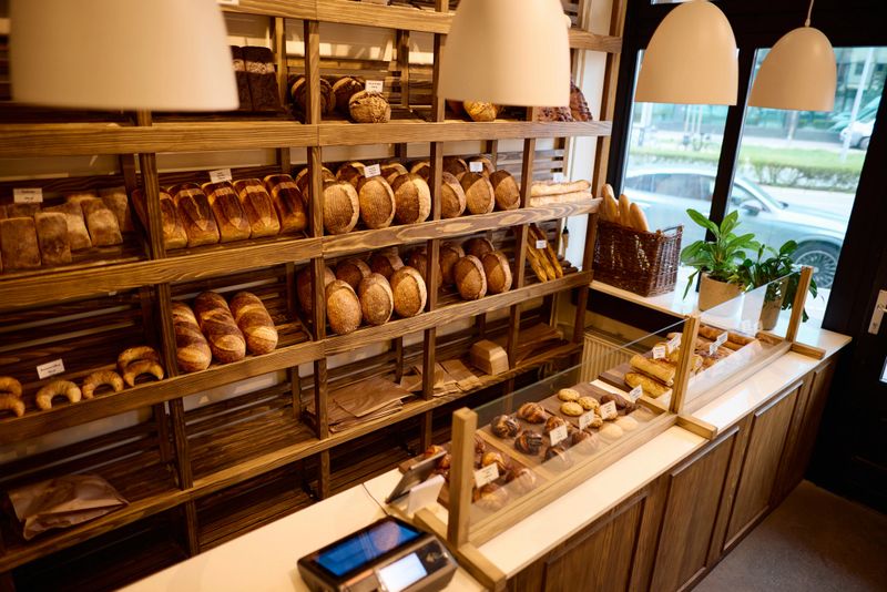 Wooden shelves brimming with an assortment of bread and pastries, creating a cozy and inviting ambiance in a charming bakery shop, enticing customers with fresh baked goods