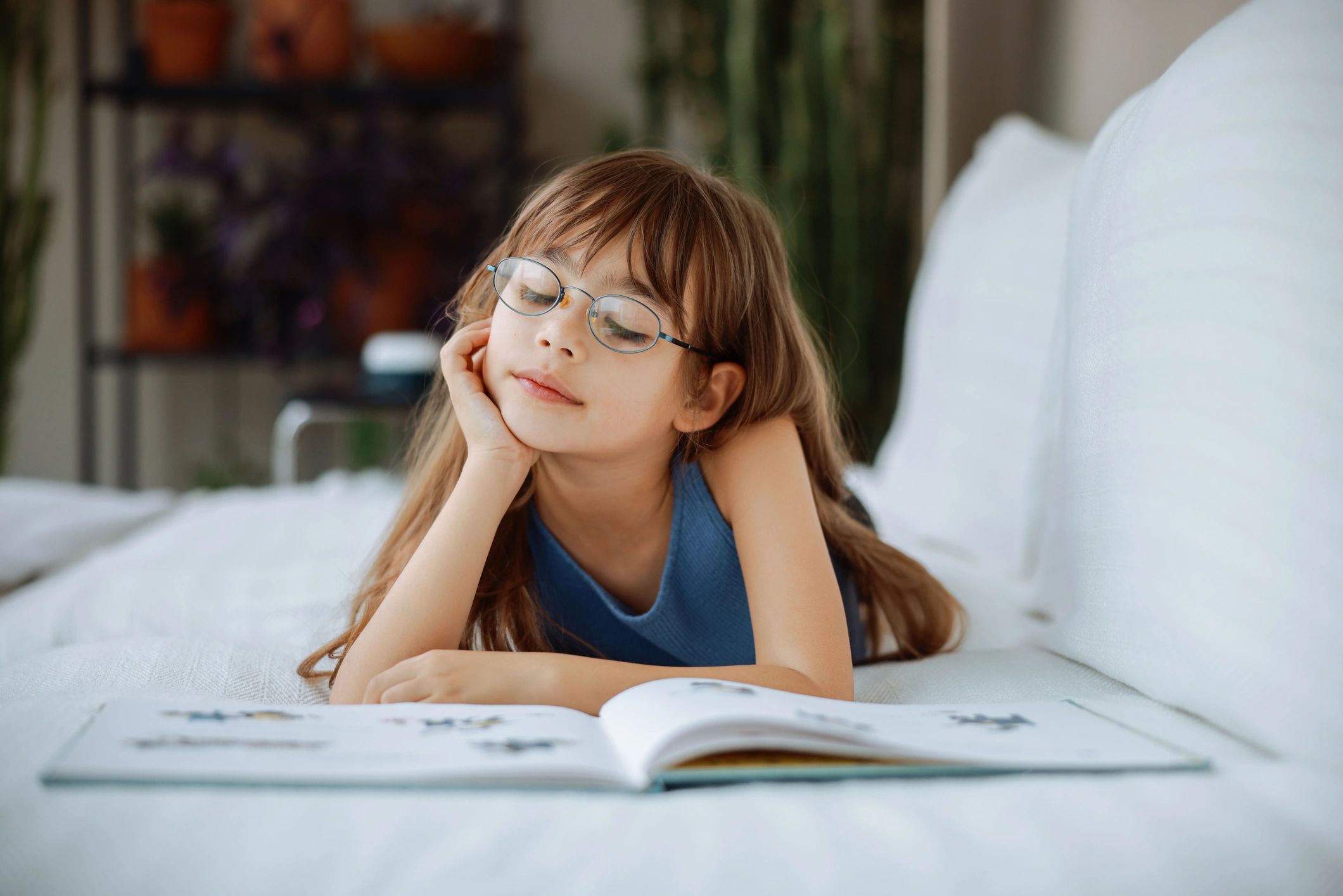 Young girl with long hair and glasses reading a book