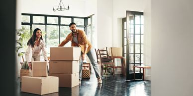 Couple moving boxes into a new home with smiles.