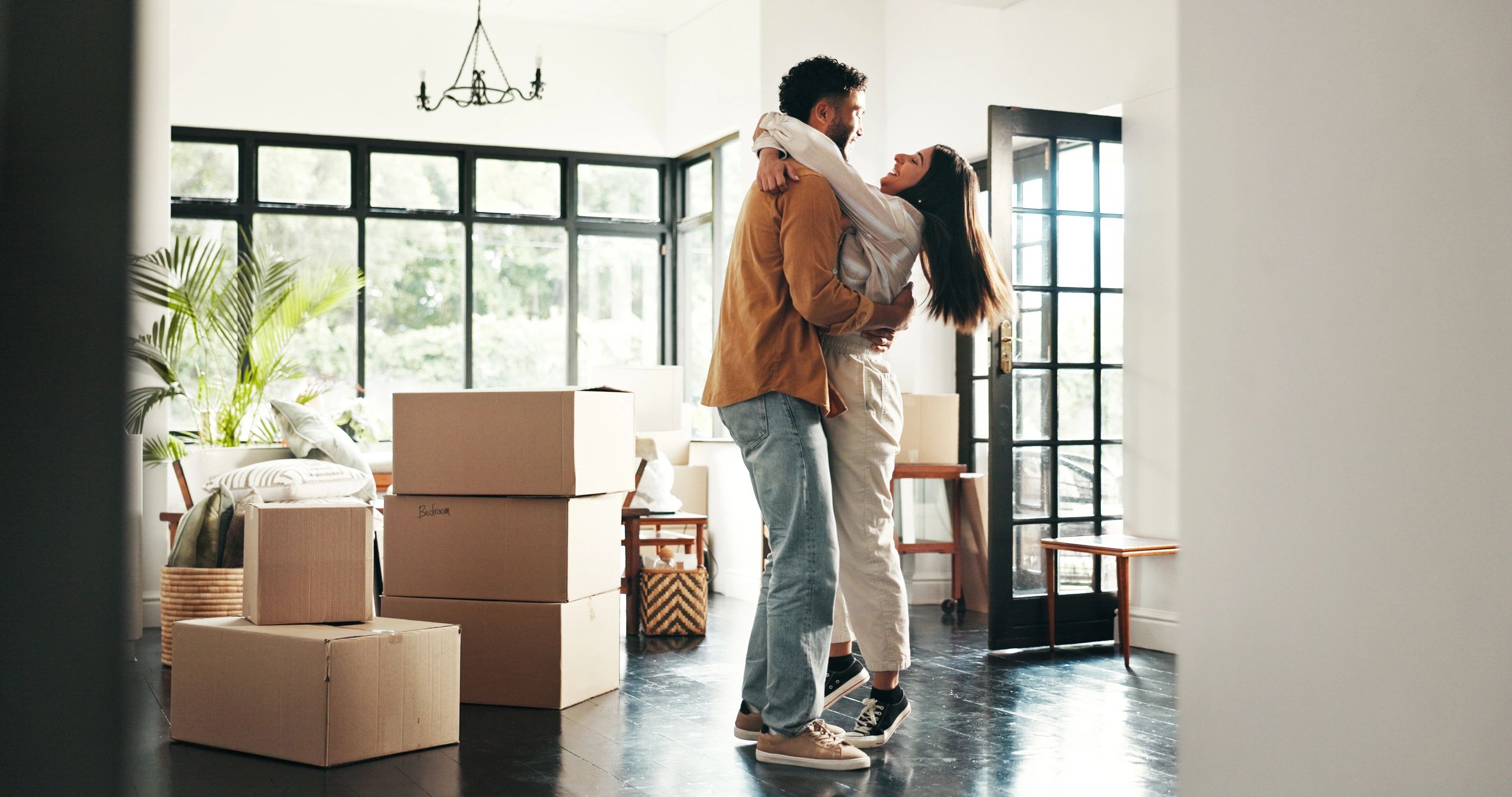 A joyful young couple embraces and smiles at each other while celebrating their move into a new home
