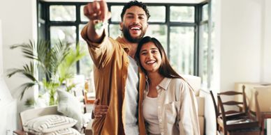 Happy couple holding house keys indoors.