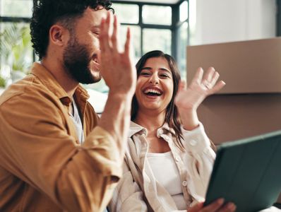 Two people happily giving a high five indoors.