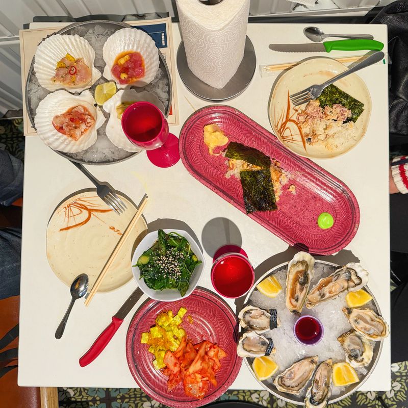 Shared table filled with assorted seafood, vegetables, rice and salads, styled with bright plates and chopsticks. Concept of fusion dining, community meal, food cultural mix, vibrant presentation