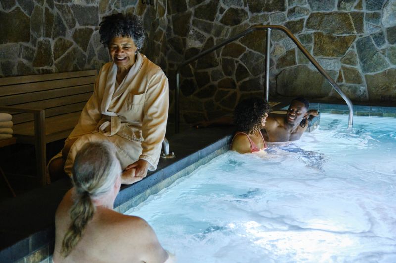 A multi-generational group relaxing in the whirlpool spa at a luxury resort hotel.