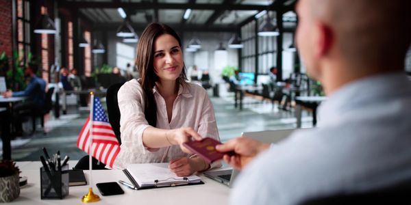 A woman hands a passport to a man in a modern office setting.