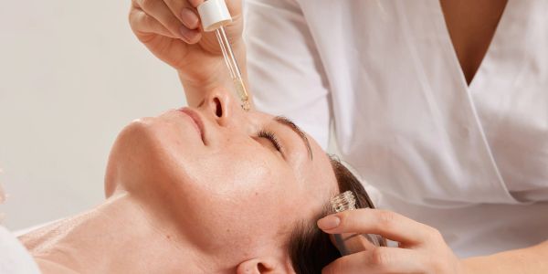 Woman receiving facial serum treatment.