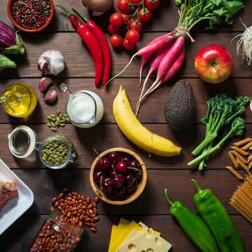 An assortment of fresh fruits, vegetables, nuts, and other healthy foods on a wooden table.