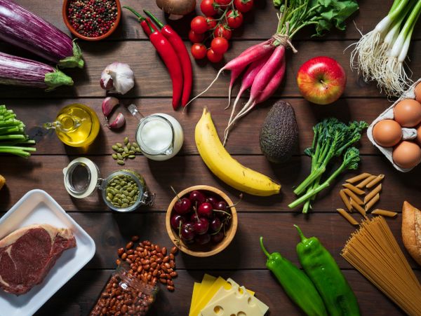 Variety of fresh fruits, vegetables, and other foods on wooden table.
