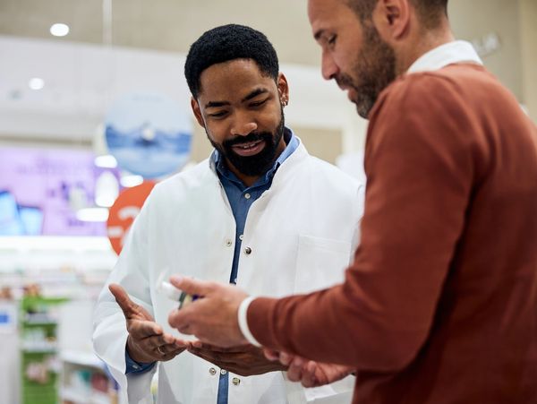 Pharmacist explaining medication usage to a customer in a pharmacy.