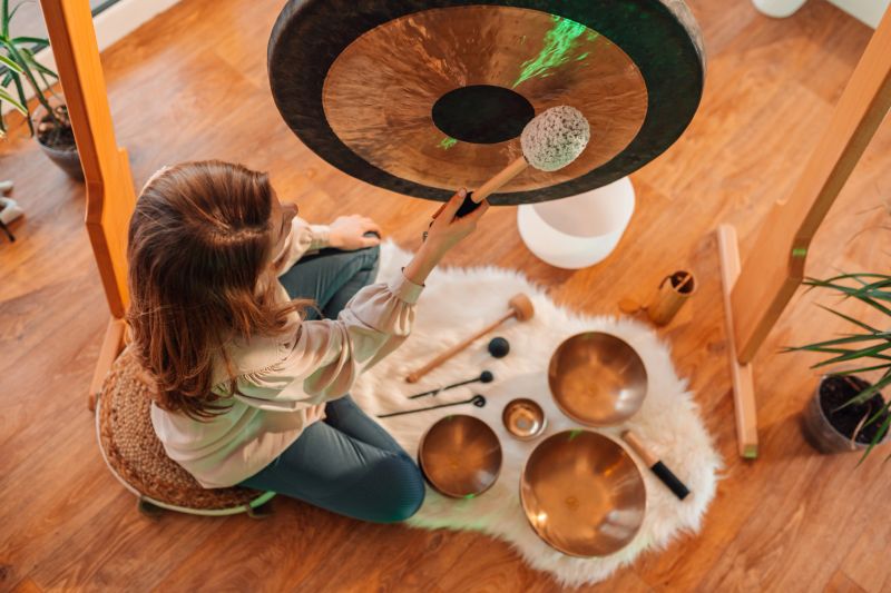 Sound therapist playing a gong during a sound healing session, creating soothing vibrations that promote relaxation and mindfulness