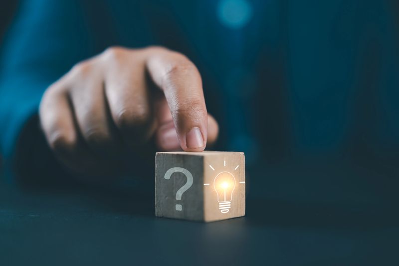 Hand touching Glowing light bulb on bright side and question mark on dark side of wooden block cube for problem solving solution and creative thinking idea innovation concept.