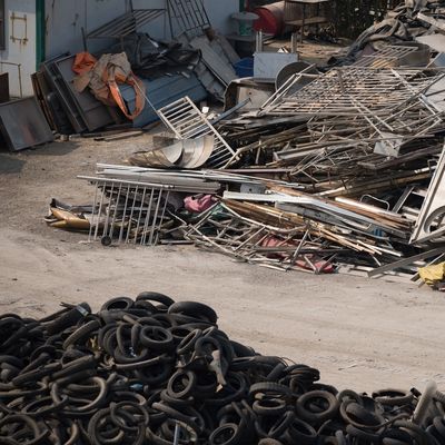 Sorted large piles of scrap metal and tires in an outdoor junkyard.