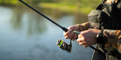 Person holding a fishing rod near a body of water.
