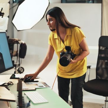 Photographer adjusting camera settings in studio.